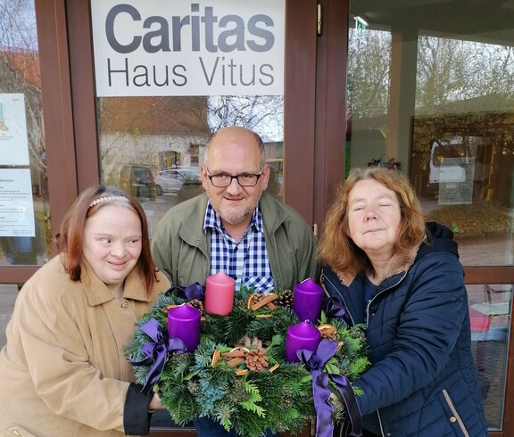 Einige Bewohner*innen vom Caritas Haus Vitus präsentieren ihren Adventkranz.