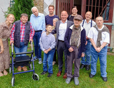 Die Bewohner*innen des Haus St. Stephan stehen auf einer Wiese und lächeln in die Kamera.