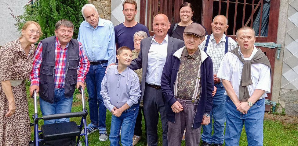 Die Bewohner*innen des Haus St. Stephan steht auf einer Wiese und lächelt in die Kamera.