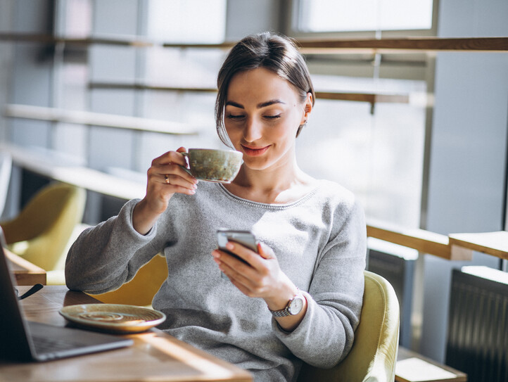 Woman sitting in a cafe drinking coffee and working on a computer