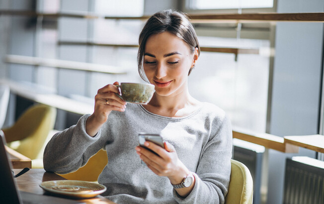 Woman sitting in a cafe drinking coffee and working on a computer